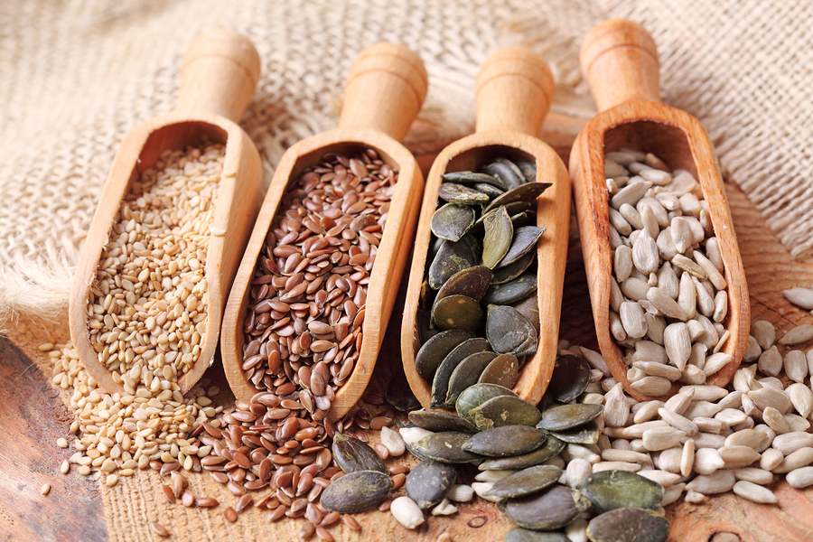Sesame, flax, pumpkin and sunflower seeds in wooden spoons